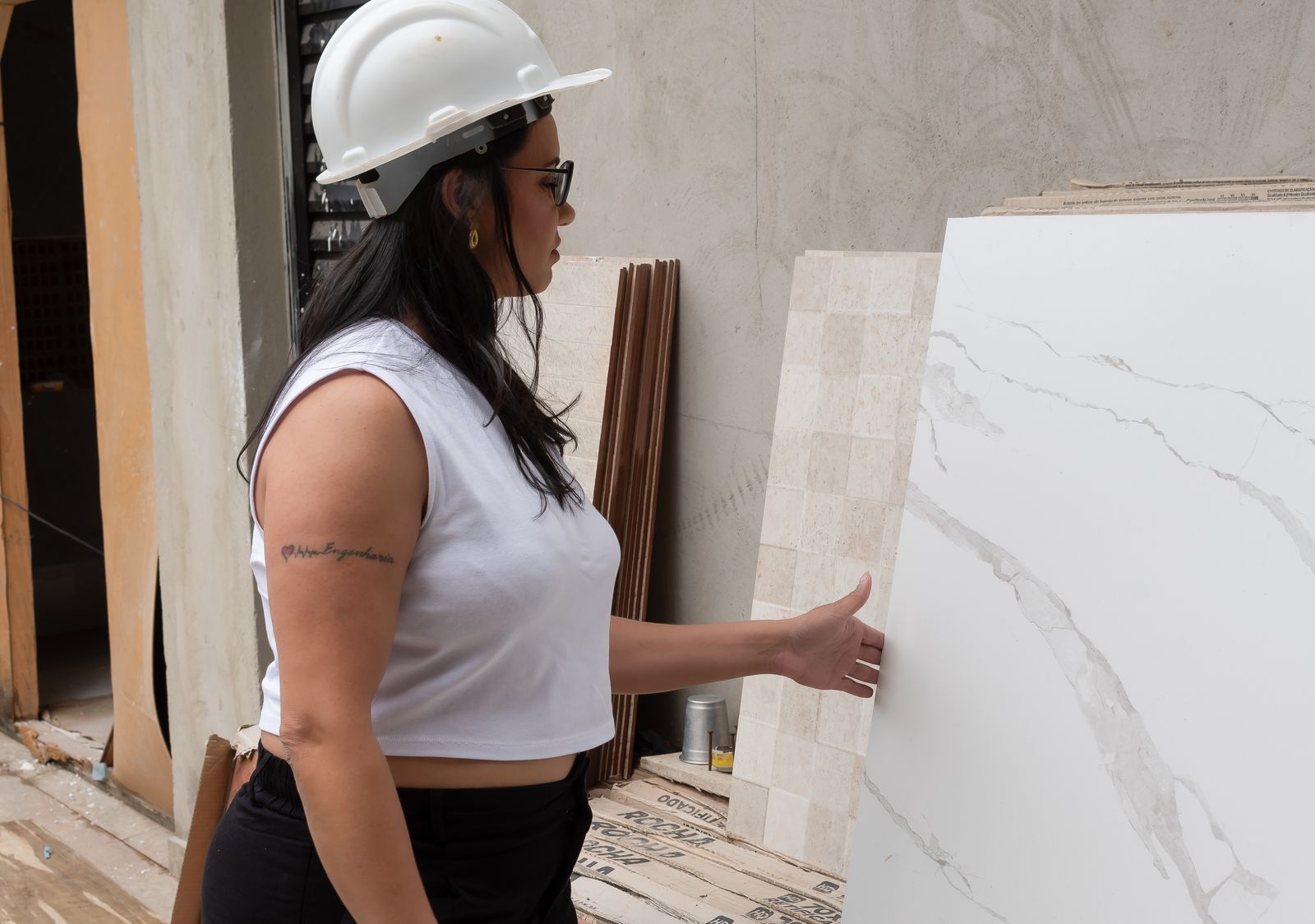 Angela Santos, de capacete, conferindo o revestimento de porcelanato em uma obra